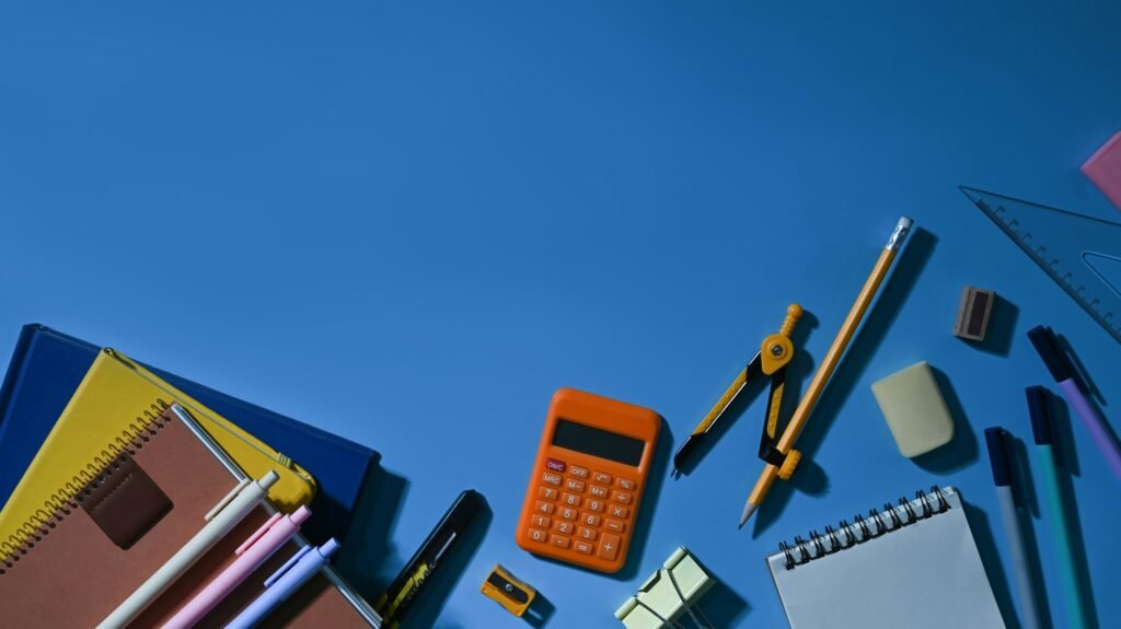 Top view of various school supplies on a blue background with empty space ready for your design.